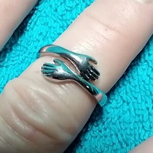 Silvertone hand hug ring adjustable
